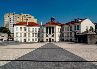 Exterior view of a building with a red tile roof and a large paved area in front of it.
