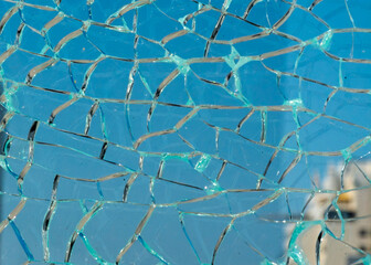 Close-up of shattered glass with a blue sky visible through the cracks.