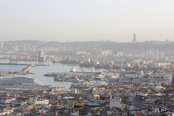 Algiers cityscape with the martyrs memorial in the distance and a busy harbor