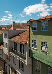 A view of buildings with red tile roofs and green walls under a blue sky.