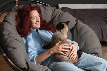 Cheerful Young Woman sitting on Couch with Dog at home