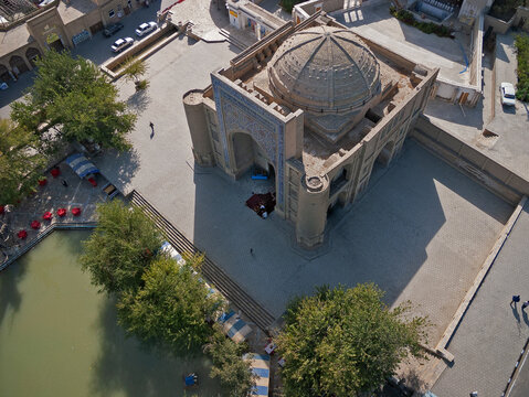 Aerial view of the serene Poi Kalyan Complex with its turquoise dome and intricate tilework reflecting in the surrounding pool, Bukhara, Bukhara Region, Uzbekistan.