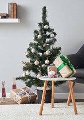 A decorated Christmas tree and wrapped gifts in a cozy modern living room.