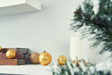 Elegant Christmas still life with golden baubles on a white shelf.