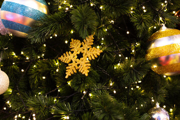 close up multicolor decoration ball with snow star and light bulb on Christmas tree pile tree at night time on holiday snowy xmas theme in december 