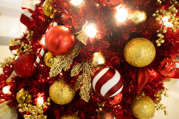 Close up red Christmas tree with red golden ball ornament and gold leaf decoration with light bulb