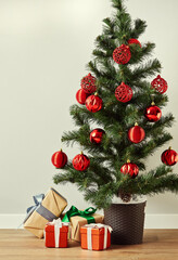 A decorated Christmas tree with a pile of wrapped gifts on the floor.