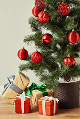 A decorated Christmas tree with a pile of wrapped gifts on the floor.