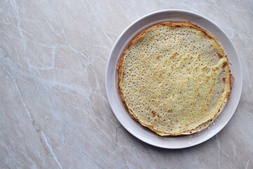 A ceramic dish with freshly baked homemade pancakes on the table