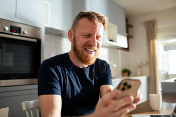 Man laughing while using smartphone