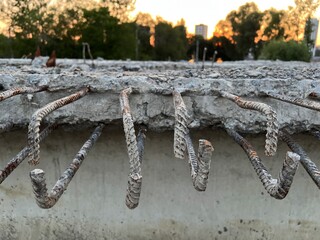 Metal reinforcement protruding from concrete blocks against the backdrop of the dark sun