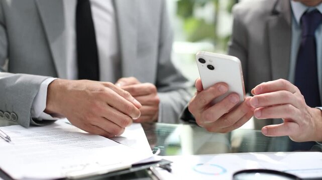 Two men are looking at a cell phone, one of them is shaking his head