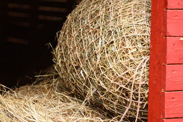 A stack of hay sits inside a bright red barn