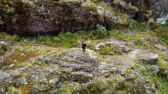 Joven viajero con mochila contemplando el paisaje desde la cima de la monta&ntilde;a en una laguna. Turista explorador en la naturaleza, disfrutando de la libertad y la aventura. estilo de vida saludable.