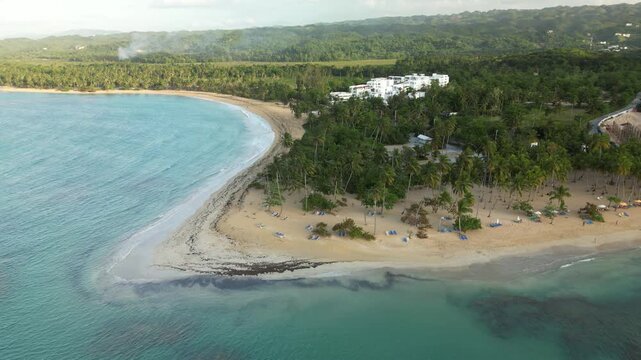 Drone capture of Punta Popy shore after rainfall, showcasing serene waves, soft light over sand and greenery. Great for nature, resort, and Caribbean travel projects