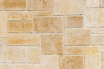 Naklejka premium Travertine, natural stone tiles, perfect for a background, creating a unique and aesthetic pattern of yellowish-beige rectangles of various sizes