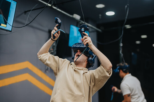 A young man immersed in a virtual reality experience, joyfully interacting with controllers, showcasing advanced VR technology in an engaging and collaborative environment.