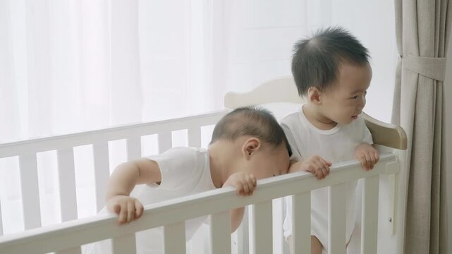 Two twin babies playing in their crib
