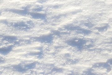Close-up of fresh snow texture with small shadows creating an abstract background pattern