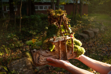 Fairy house building activity in nature built with natural materials such as moss, twigs, bark, and wood