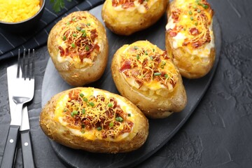 Tasty stuffed baked potatoes served on black textured table, closeup