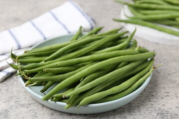 Fresh green bean pods on grey textured table, closeup