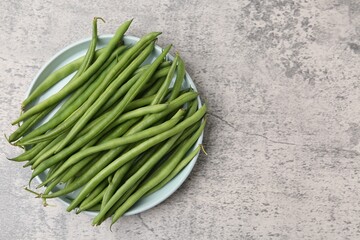 Fresh green bean pods on grey textured table, top view. Space for text