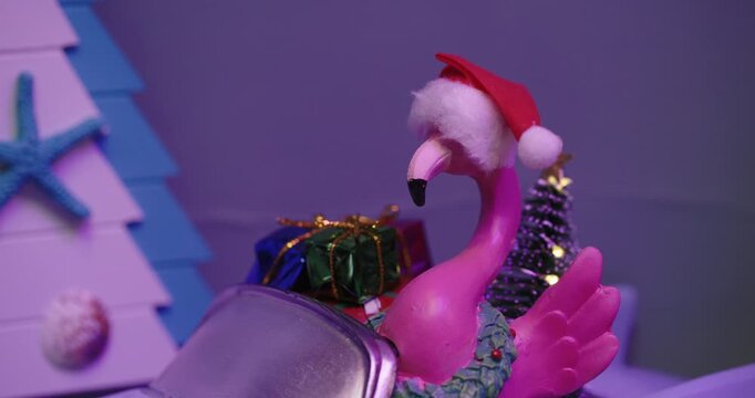 Flamingo in a Santa hat riding a toy convertible in colored light
