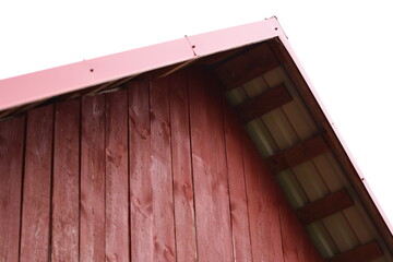 A curious cat sits atop the roof of a bright red barn, enjoying the view
