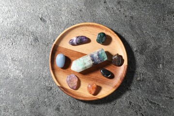 Different beautiful gemstones on grey table, top view