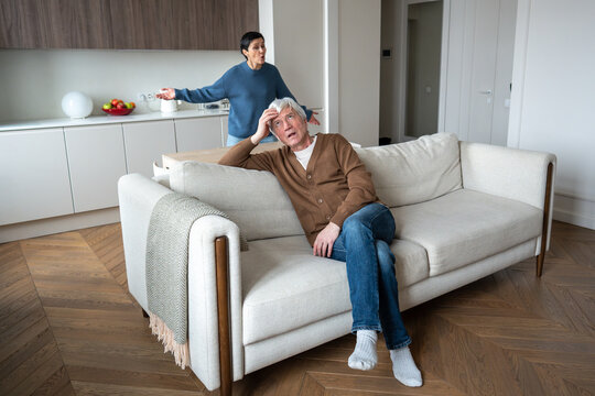 Heated argument in mature family. Frustrated agitated wife nagging criticizing indifferent lazy rude husband on couch. Household conflict, marriage tension, resentment, unbalanced responsibilities