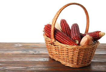 Obraz premium Ripe red corn cobs in basket on wooden table against white background