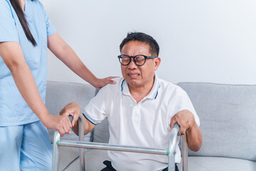 Obraz premium Caring nurse assists elderly man with walker as he expresses discomfort during rehabilitation session in comfortable indoor setting