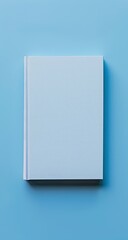 A light blue book with a blank cover rests on a matching background, presented in a simple, overhead shot