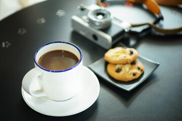 hot black coffee in white cup with chocolate chip cookies on black table