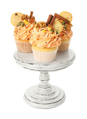 Delicious cupcakes with sprinkles, spices, cookies and nuts on stand isolated on white. Autumn atmosphere
