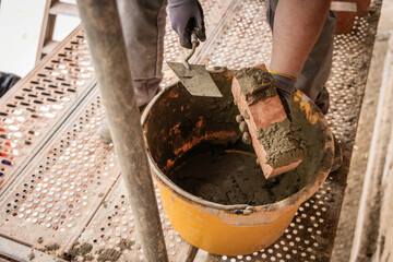 Maurer mit Backstein und Mörtel in der Hand.