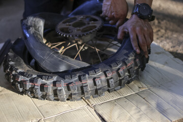 Focused individual diligently repairs flat motorcycle tire, carefully removing damaged inner tube for quick replacement. close up view captures hands process of vehicle maintenance, showcasing