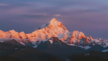 Snow-capped mountain peak illuminated by golden sunrise light against a purple sky