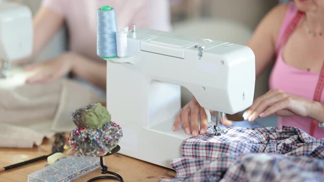 Female hands of seamstress sewing clothes on sewing machine in sewing workshop close-up