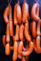 Fototapeta premium Traditional sausages are suspended in market, displaying artisanal food craftsmanship local culinary heritage.