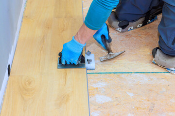 Skilled carpenter carefully installs laminate flooring in living room, focusing on detail alignment.