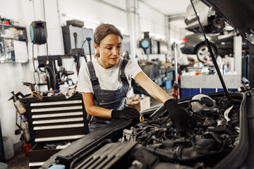A highly skilled female mechanic meticulously examines a car engine in a wellequipped and organized auto repair shop