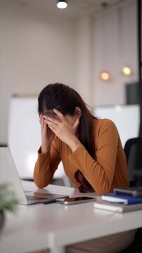 Adult Asian businesswoman feeling stress and burnout at office desk dealing with work pressure deadline and professional challenges