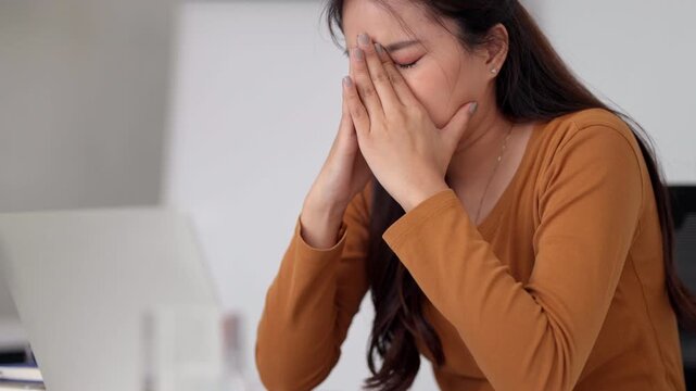 Adult Asian woman overwhelmed experiencing burnout frustration headache stress work fatigue professional life challenges modern office environment mental health awareness