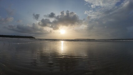 Idyllic Coastal Sunrise with Gentle Waves, Dramatic Clouds, and Mirror-Like Reflections