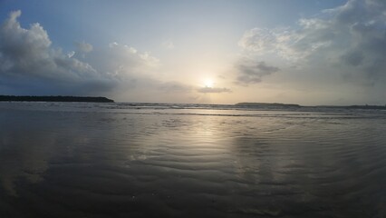 A Tranquil and Moody Seascape Capturing the Vibrant Light of Sunrise or Sunset Reflected Symmetrically on Wet Sand and Water.
