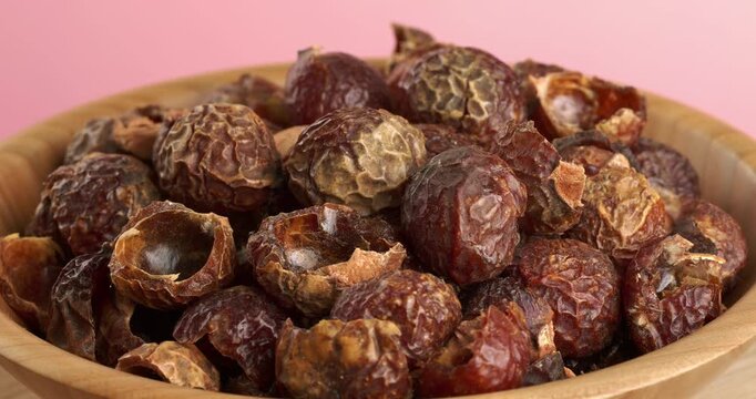 Soap nuts in wooden bowl, close-up footage on a rotating table.