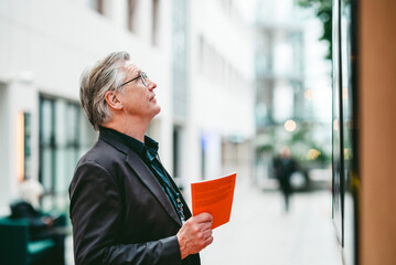 Senior male business expert reading board at convention center lobby