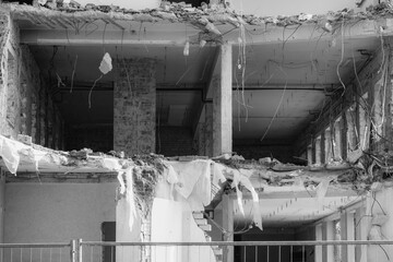 Building demolition exposes interior structure with debris and exposed wires in urban area